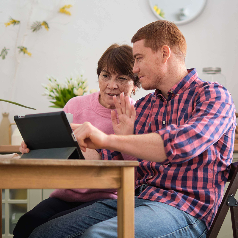 Man helping his mother use a tablet.