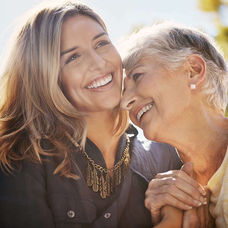 Smiling care partner and her mother embracing.