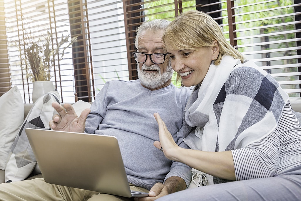 Couple happily waving to laptop during video call