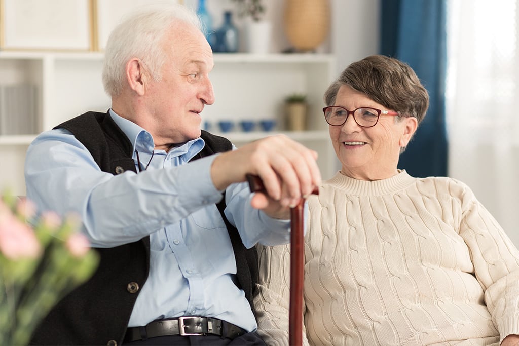 Mature adult man with a cane talking with a mature adult female