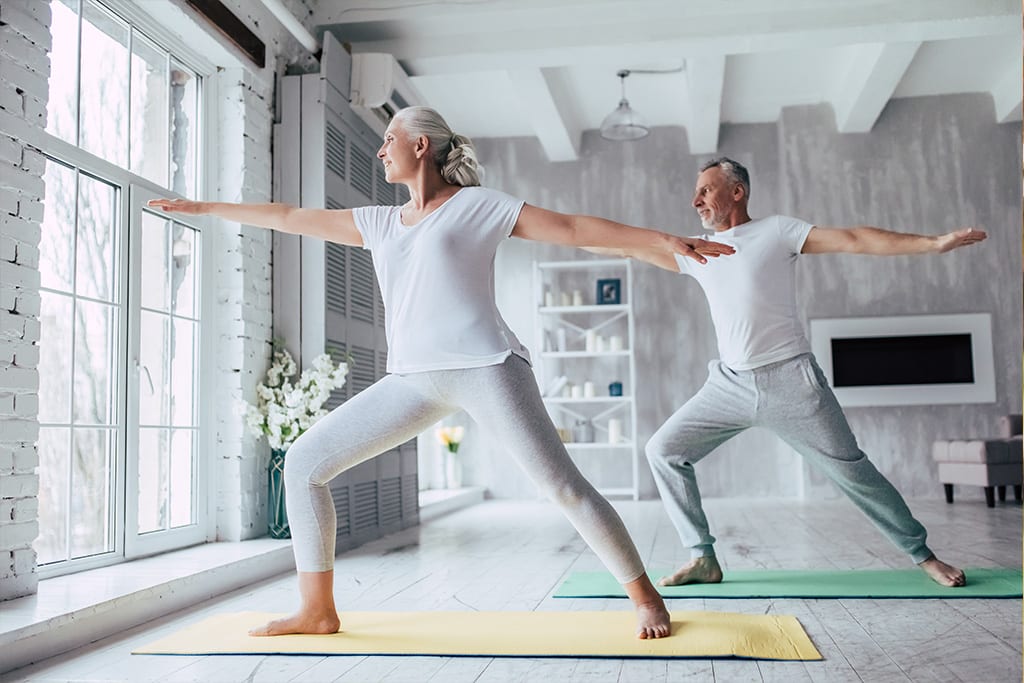 Mature adult couple doing yoga as part of their self-care routine