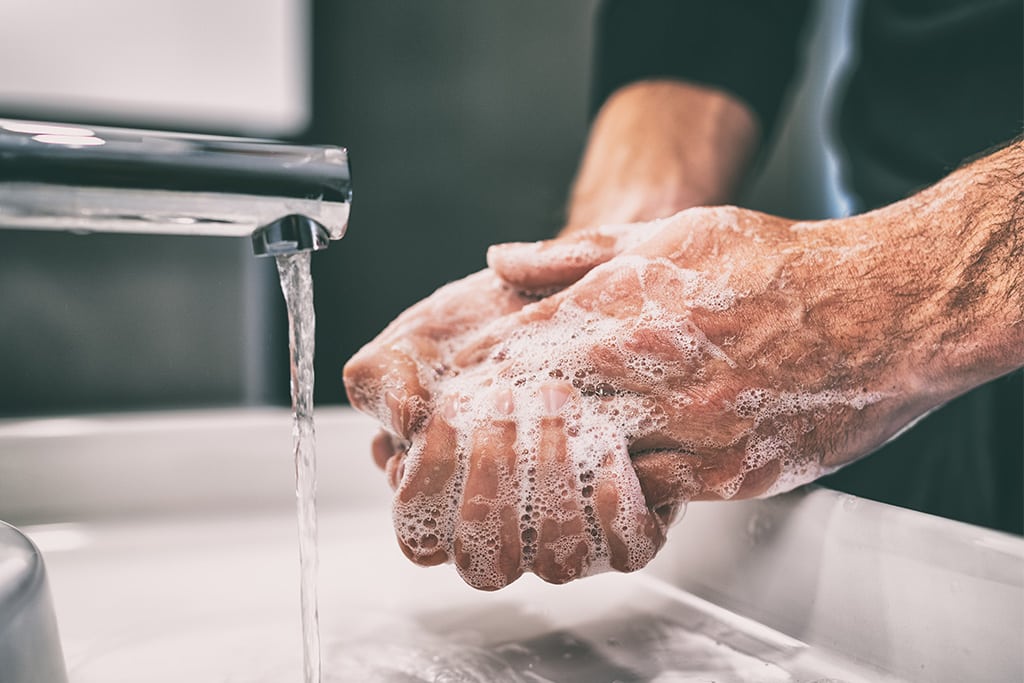 Photo of a man washing his hands with soap at a sink