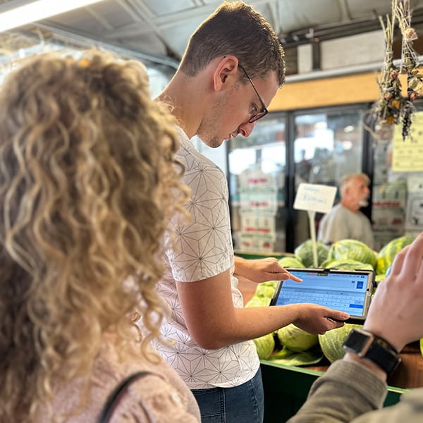 Young man uses his Lingraphica AAC device to shop at the local farmers market.