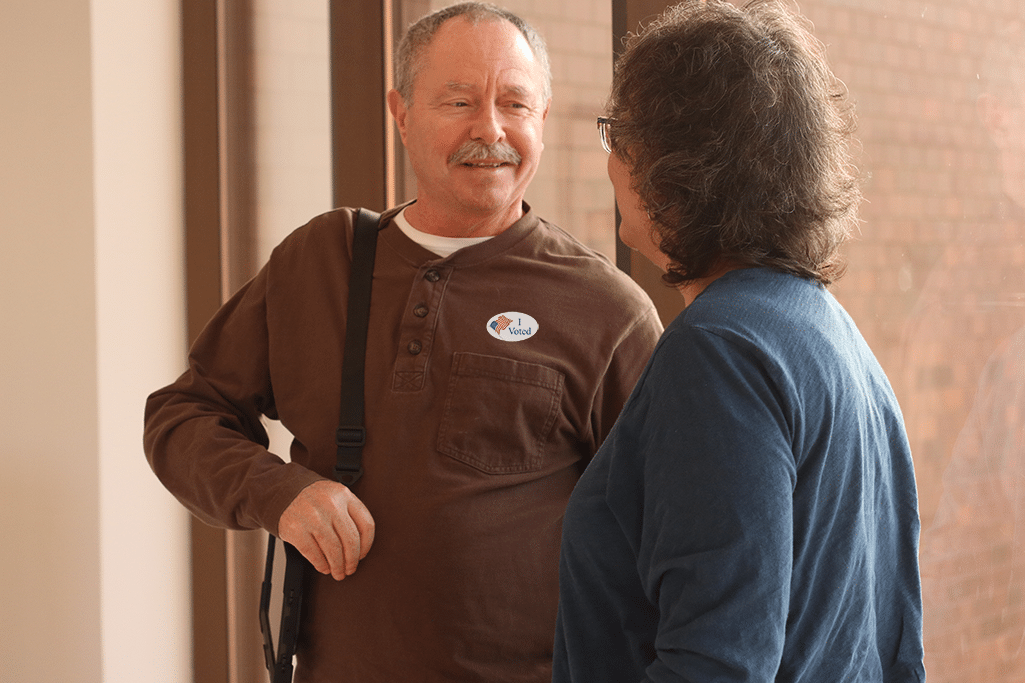 man with aac device and i voted sticker