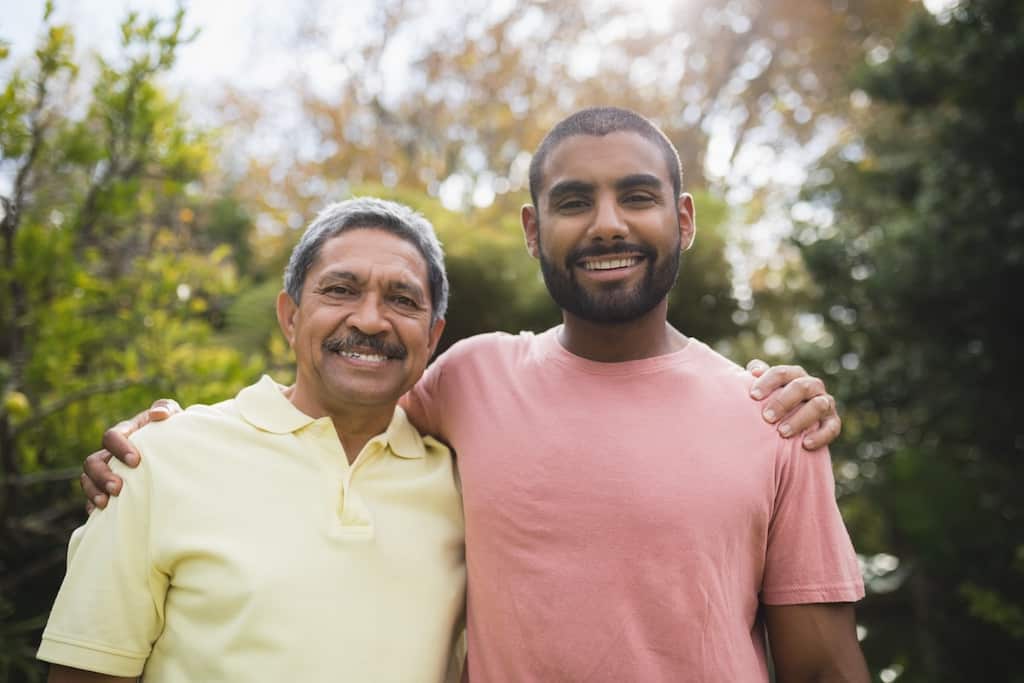 Portrait of smiling man with his father standing at park