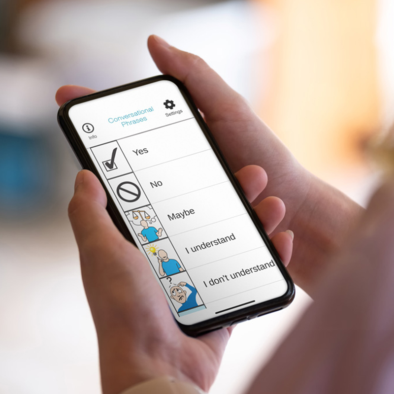 Close-up of hands holding a smart phone running Lingraphica's SmallTalk app.