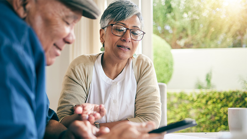 Photo of man and woman talking and holding a mobile phone.