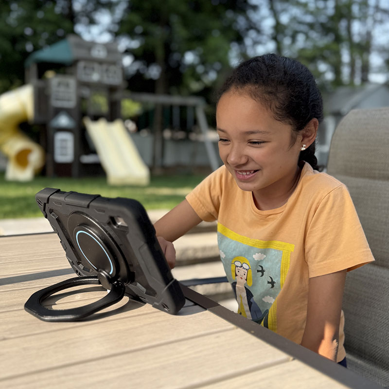 Girl using MiniTalk™ AAC device outside.