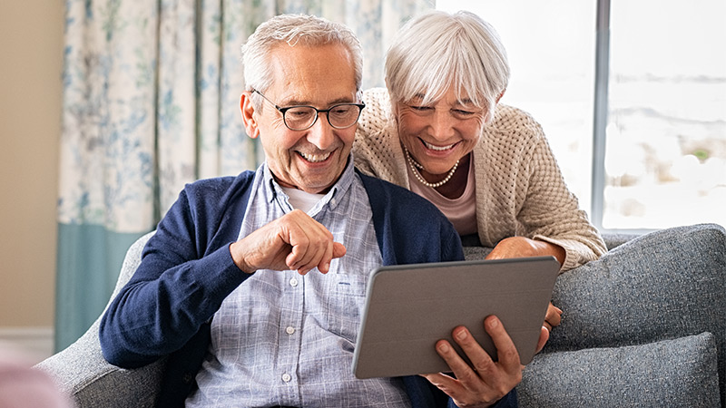 Happy couple joining online group session on their tablet from home.