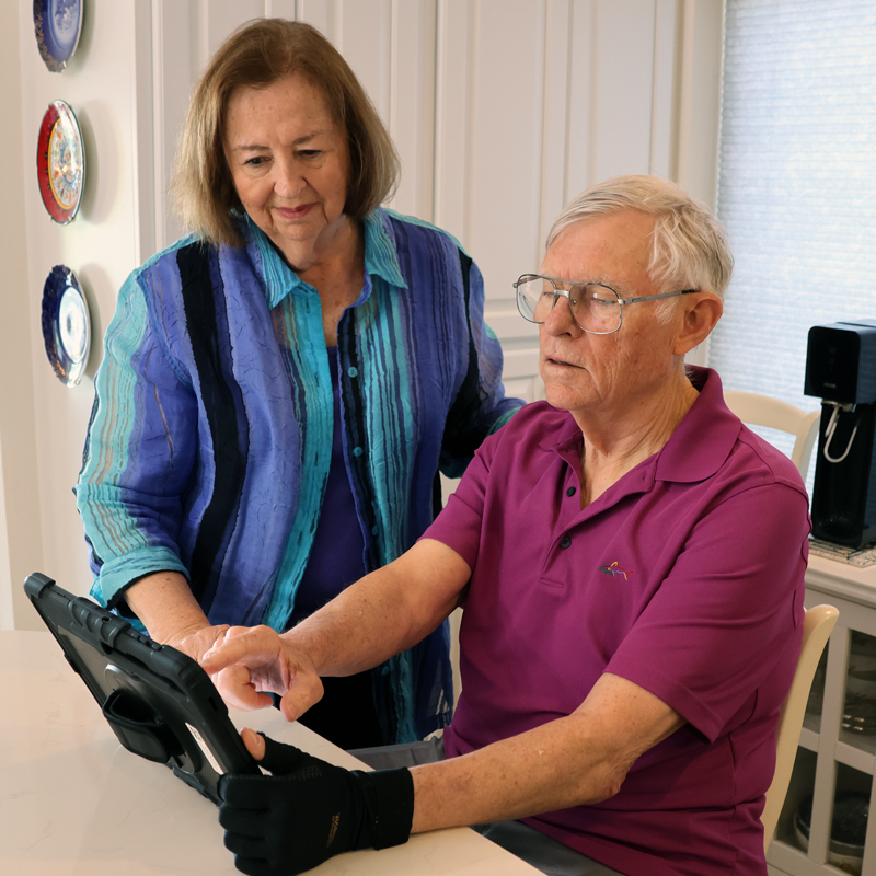 Man using a TouchTalk™ Plus AAC device with his spouse.