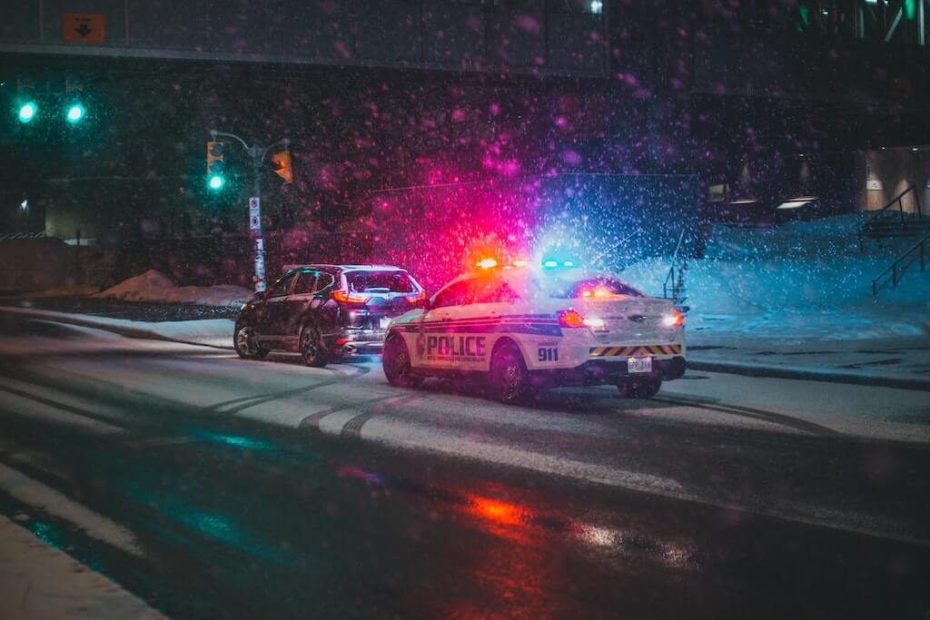photo of a police car with its red and blue lights lit up behind a SUV