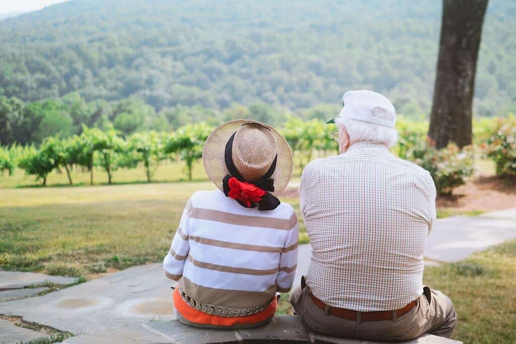 senior couple sitting with backs to camera outdoors