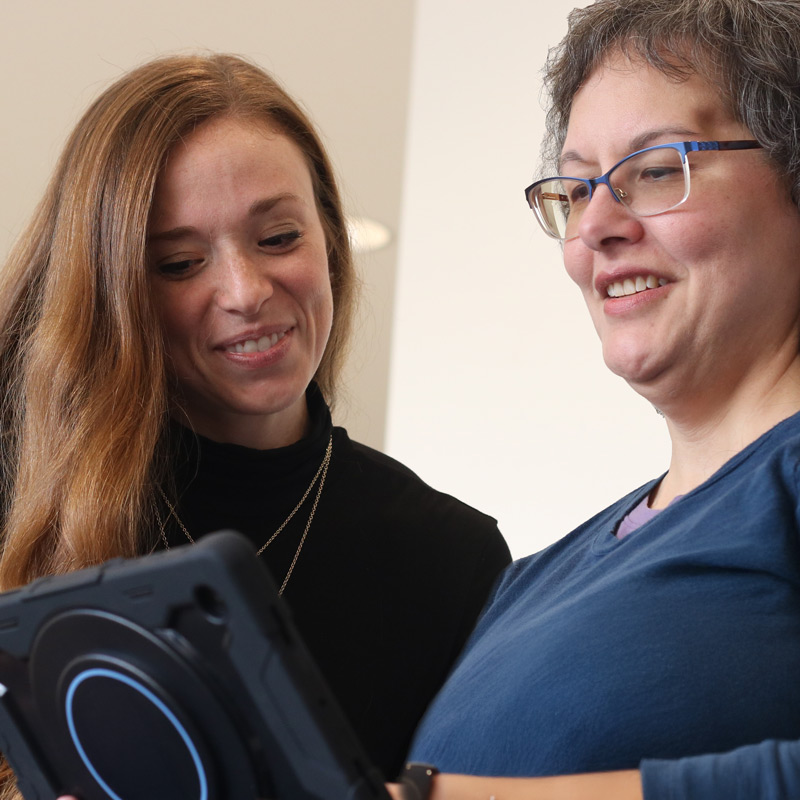 Female SLP showing a Lingraphica TouchTalk device to a female client.