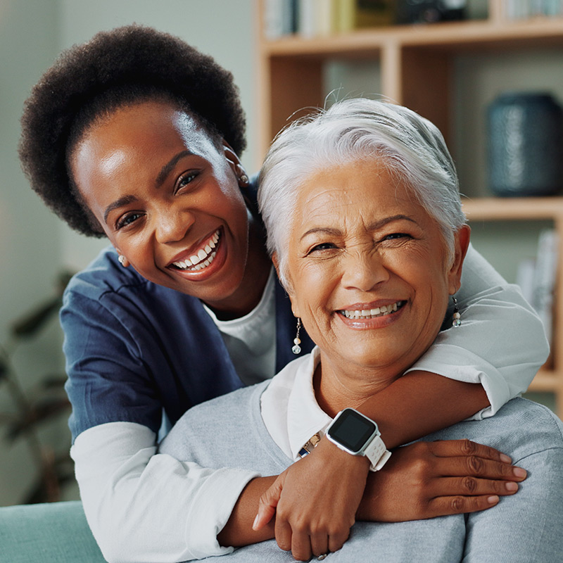 Smiling clinician embracing their female client in a home setting.