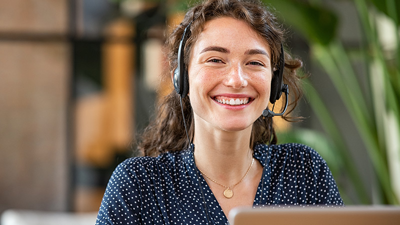 Photo of a smiling customer service representative wearing a telephone headset.