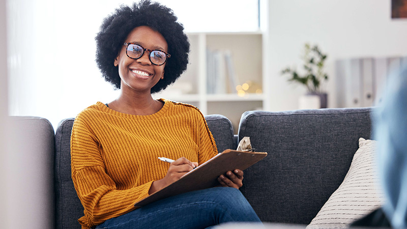 Smiling SLP taking notes on her clipboard.