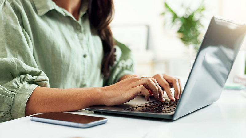 Close up of a woman's hands typing on a laptop.