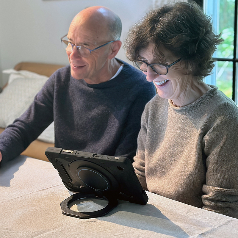 Woman smiling using TouchTalk™ in dining room.