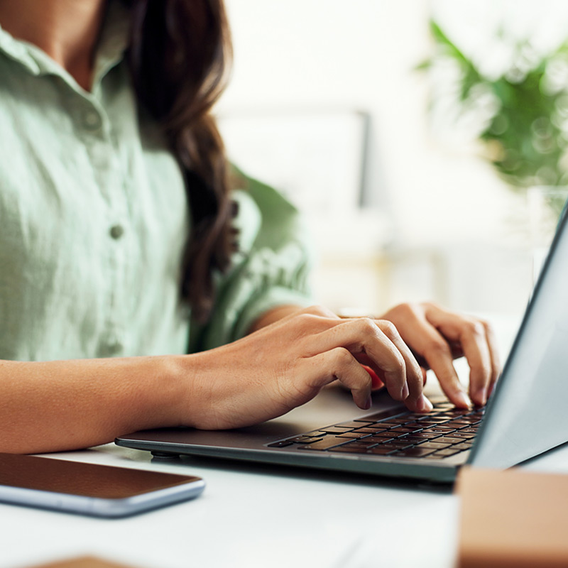 Close up of a woman's hands typing on a laptop