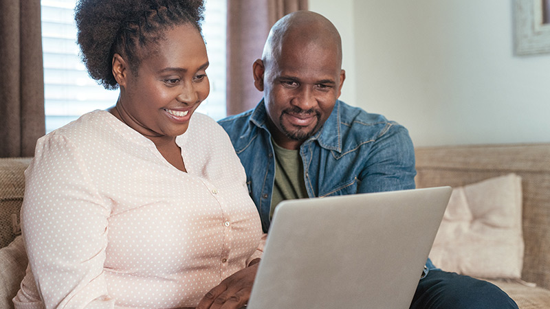 Photo of a young couple looking at a laptop at home.